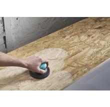 Une personne ponce une planche de bois avec une ponceuse manuelle.