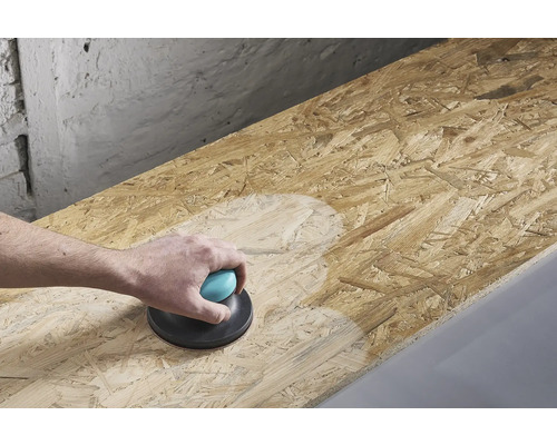 Une personne ponce une planche de bois avec une ponceuse manuelle.