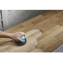 Une personne ponce une plaque de bois avec une ponceuse excentrique.