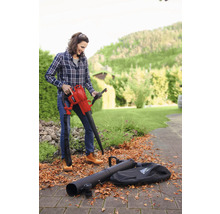 Une femme utilise un aspirateur de feuilles avec des accessoires dans le jardin.