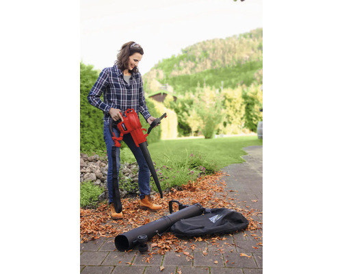 Une femme utilise un aspirateur de feuilles avec des accessoires dans le jardin.