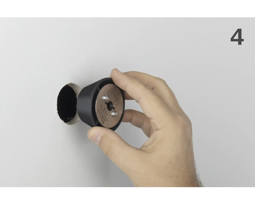 Une main tient le foret à bouchons Wolfcraft devant un trou de forage.