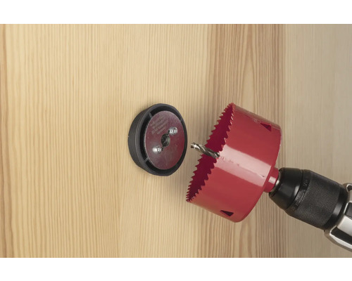 Scie cloche avec perceuse perçant un trou dans une porte en bois