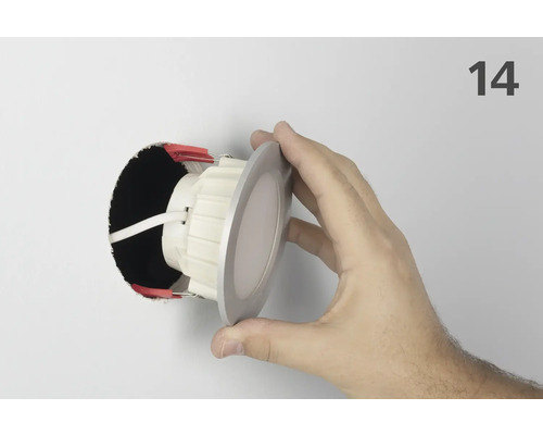 Installation d'un spot encastrable au plafond dans un trou avec la main