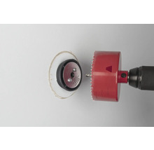 Perceuse avec scie cloche coupant un trou dans un mur