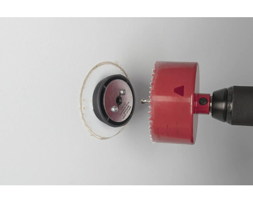 Perceuse avec scie cloche coupant un trou dans un mur