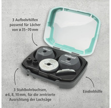 Kit de centrage pour scie cloche Wolfcraft avec trois guides de perçage, trois douilles de perçage en acier et une aide à l'enfoncement dans une boîte.