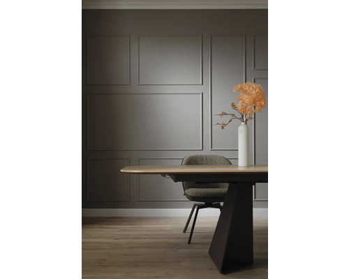 Table de salle à manger avec chaise et vase de fleurs devant un mur orné de moulures