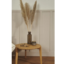 Arrangement décoratif avec de l'herbe de pampa dans un vase, une bougie et des lunettes sur une table en bois