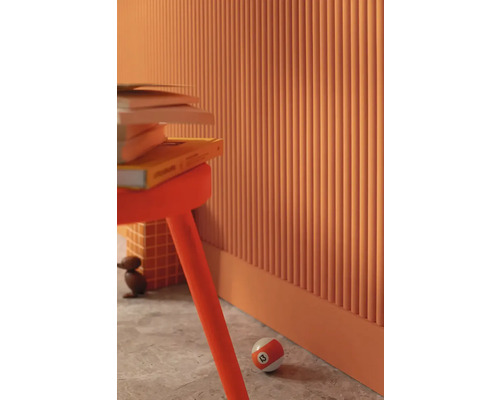 Vue d'intérieur avec une pile de livres sur un tabouret devant un mur à lattes verticales