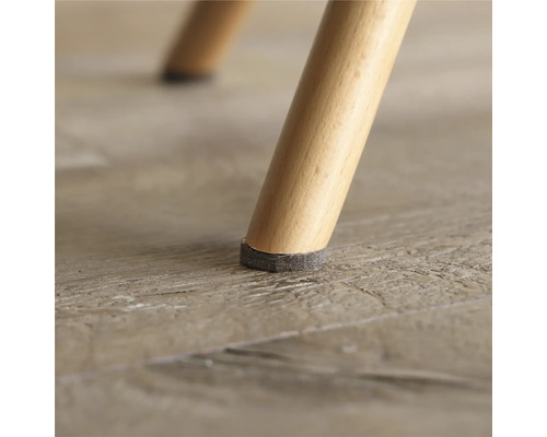 Nahaufnahme eines Stuhlbeins mit Filzgleiter zum Schutz des Bodens.