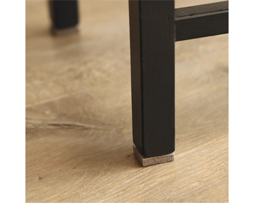 Detailansicht eines schwarzen Möbelbeins mit einem Filzgleiter zum Schutz des Bodens.