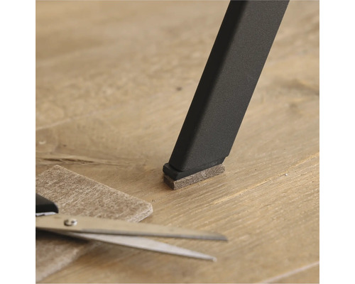 Filzgleiter an einem Stuhlbein mit Schere und Filzstück auf dem Boden