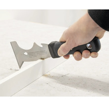 Eine Person verwendet einen Multifunktionsschaber zum Entfernen von Material von einer Oberfläche.