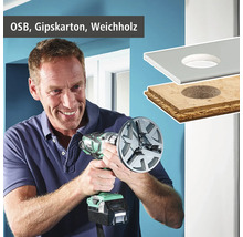 Un homme perce un trou dans un panneau OSB, un panneau de gypse et du bois tendre avec une scie trépan