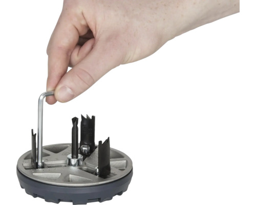 Une main manipule une scie à trou avec une clé Allen