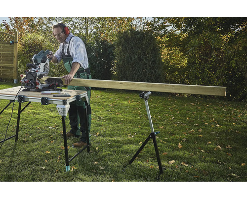 Handwerker sägt Holz mit einer Kappsäge auf einem Sägetisch im Garten.