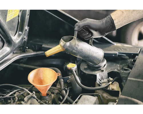 L'huile moteur est ajoutée à l'aide d'un entonnoir et d'un bidon d'huile