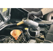 L'huile moteur est ajoutée à l'aide d'un entonnoir et d'un bidon d'huile