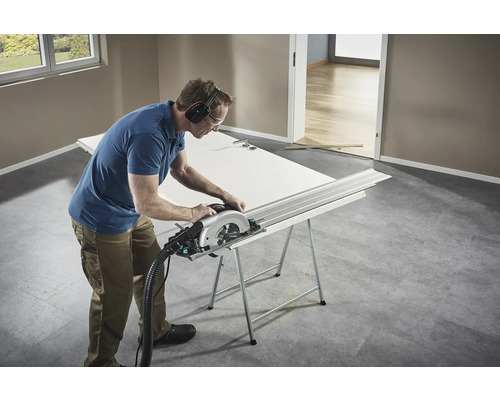 Artisan coupant une porte avec une scie circulaire sur un établi.