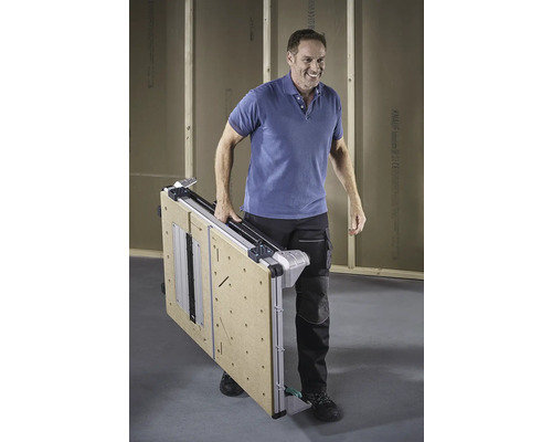 Ein Mann trägt einen zusammengeklappten Werktisch.