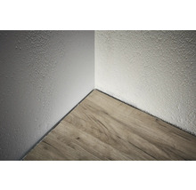 Coin d'une pièce avec plancher en bois et mur texturé