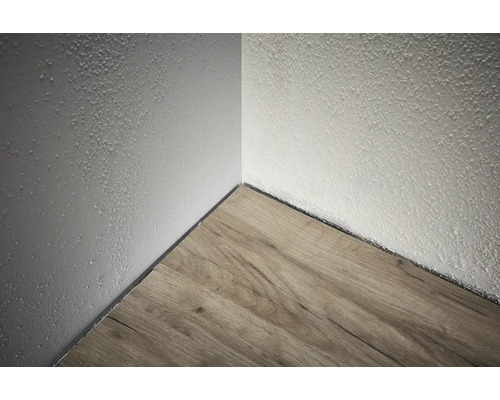 Coin d'une pièce avec plancher en bois et mur texturé