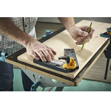 Une personne utilise un gabarit de traçage et un crayon sur une planche en bois.