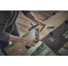 Une personne utilise un établi, une équerre et un stylo pour travailler un morceau de stratifié.