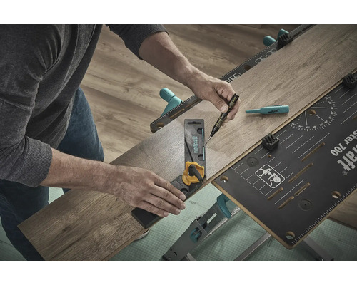 Une personne utilise un établi, une équerre et un stylo pour travailler un morceau de stratifié.