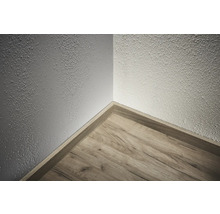 Coin d'une pièce avec plancher en bois et plinthe