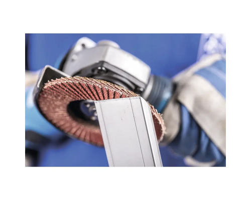 Un homme utilise une meule à lamelles sur une pièce métallique.