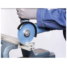 Une personne coupe un profilé en aluminium avec une meuleuse d'angle dans un étau.