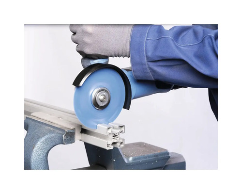 Une personne coupe un profilé en aluminium avec une meuleuse d'angle dans un étau.