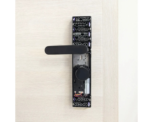 Garniture de porte numérique avec piles et poignée de porte noire sur une porte.