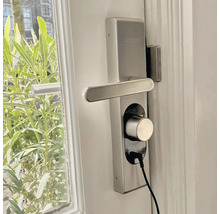 Serrure de porte Loged avec poignée et câble de charge sur une porte blanche