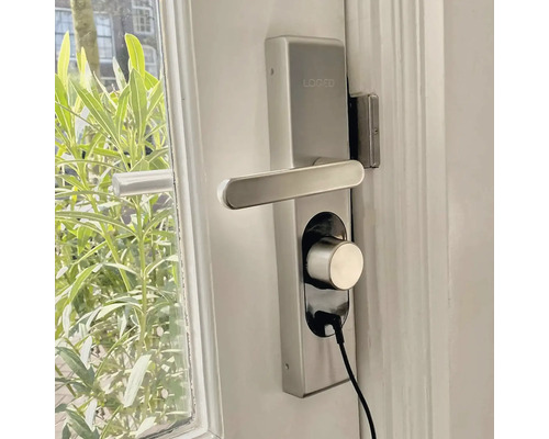 Serrure de porte Loged avec poignée et câble de charge sur une porte blanche
