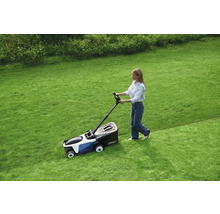 Eine Frau benutzt einen Rasenmäher auf einer Rasenfläche.