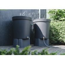 Zwei graue Regentonnen auf einer Holzterrasse mit Anschluss für einen Gartenschlauch und einem Wasserhahn.