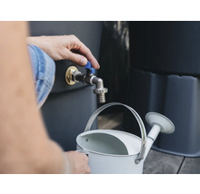 Person befüllt eine Giesskanne an einem Regenfasshahn