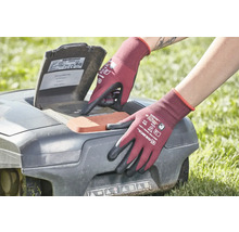 Une personne portant des gants de jardinage utilise un robot tondeuse à gazon.