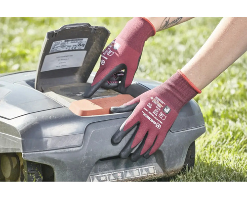 Une personne portant des gants de jardinage utilise un robot tondeuse à gazon.