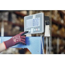 Une personne utilise une balance industrielle numérique avec un gant de travail