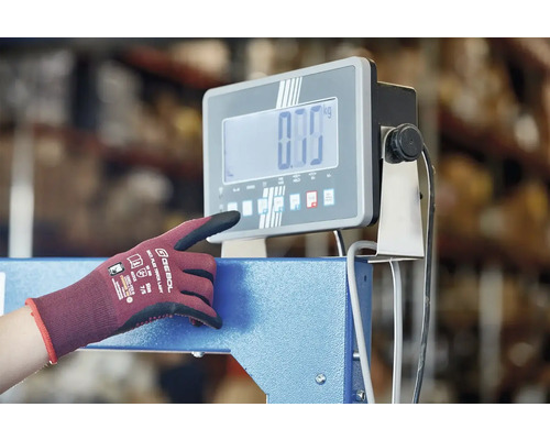 Une personne utilise une balance industrielle numérique avec un gant de travail