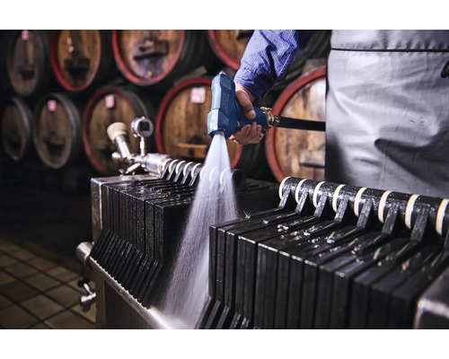 Reinigung eines Plattenfilters mit einer Spritzpistole in einer Weinkellerei.