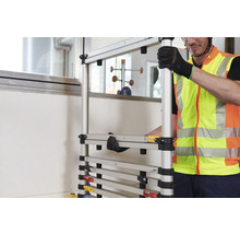 Un homme en gilet de sécurité assemble un échafaudage modulaire.