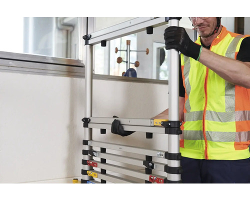 Un homme en gilet de sécurité assemble un échafaudage modulaire.