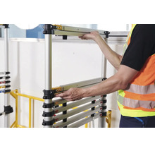 Une personne assemble un échafaudage roulant en aluminium.