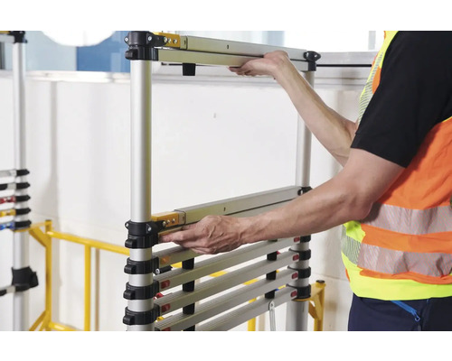 Une personne assemble un échafaudage roulant en aluminium.