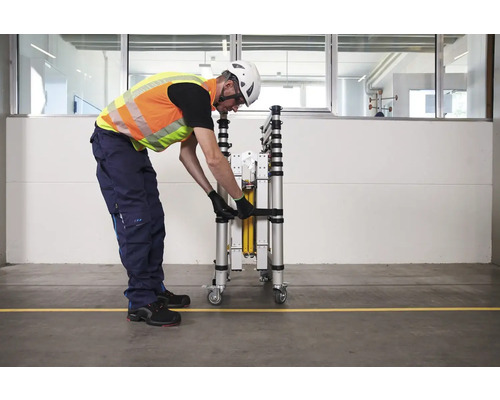 Une personne sécurise un échafaudage roulant plié avec une sangle.